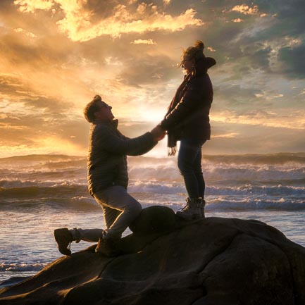 A parent and child silhouetted on the coast at sunset.