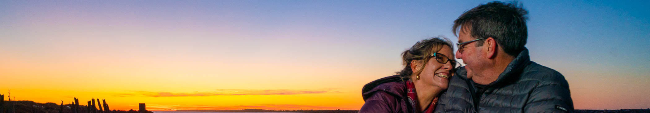 A couple enjoying the sunset on the coast.