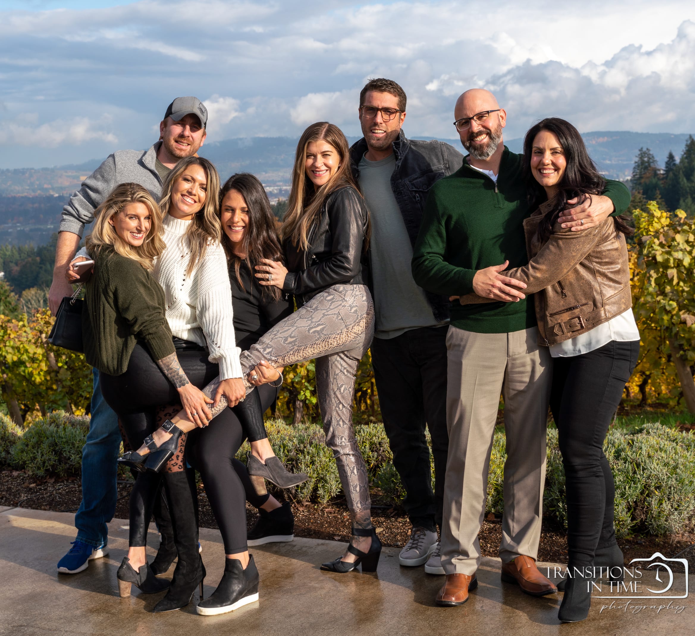 A large family gathers together in a vineyard with the valley behind them.
