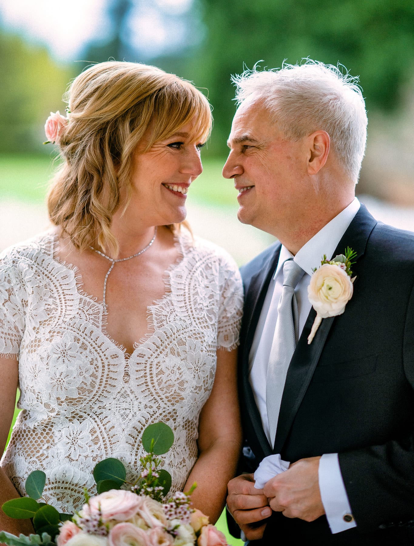 A bride and groom hold each other close in soft garden light.