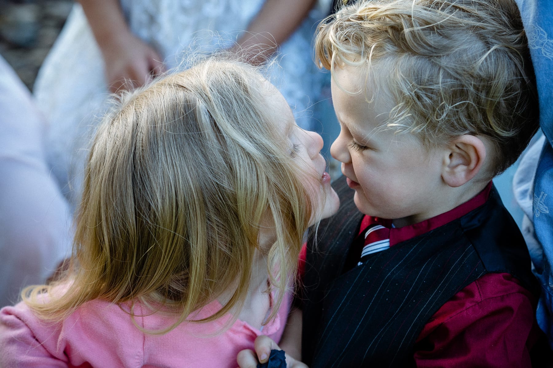 A flower girl and ring bearer touch noses at a wedding.