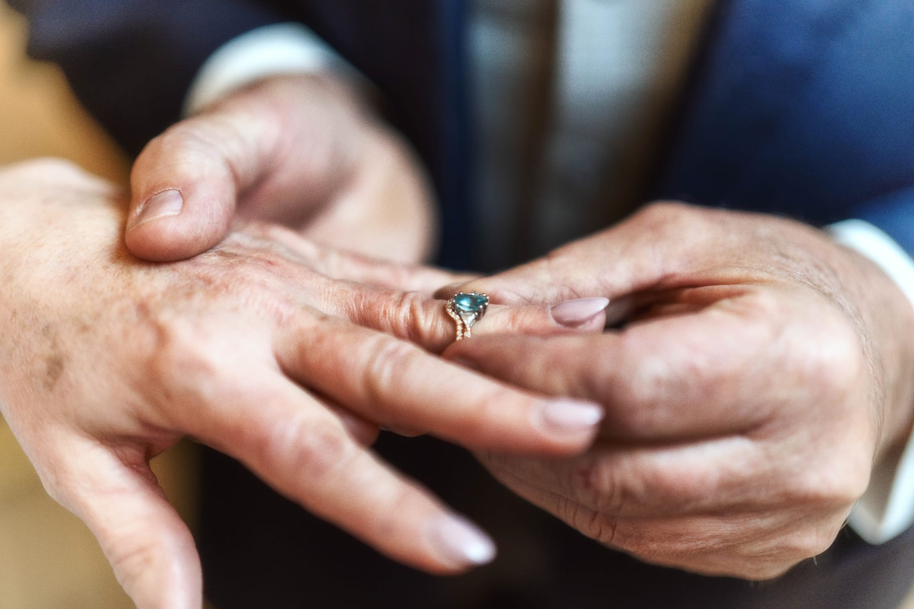 A close view of hands as a wedding ring is placed on a finger.