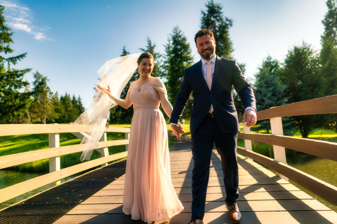 A bride walking toward the camera with the groom behind her.